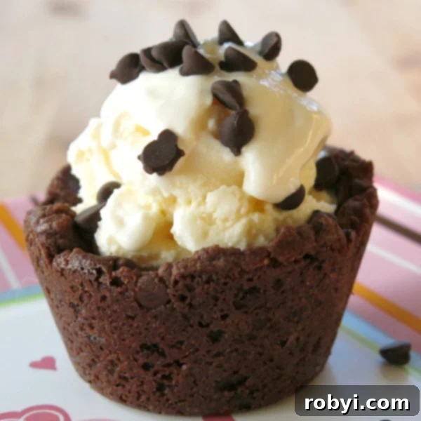 A perfectly baked Double Chocolate Chip Cookie Cup filled with vanilla ice cream and topped with extra chocolate chips, ready for a delightful indulgence.