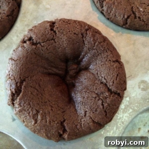 Double Chocolate Chip Cookie dough in muffin tin with a slight, natural indentation after being partially cooked, awaiting the final shaping.