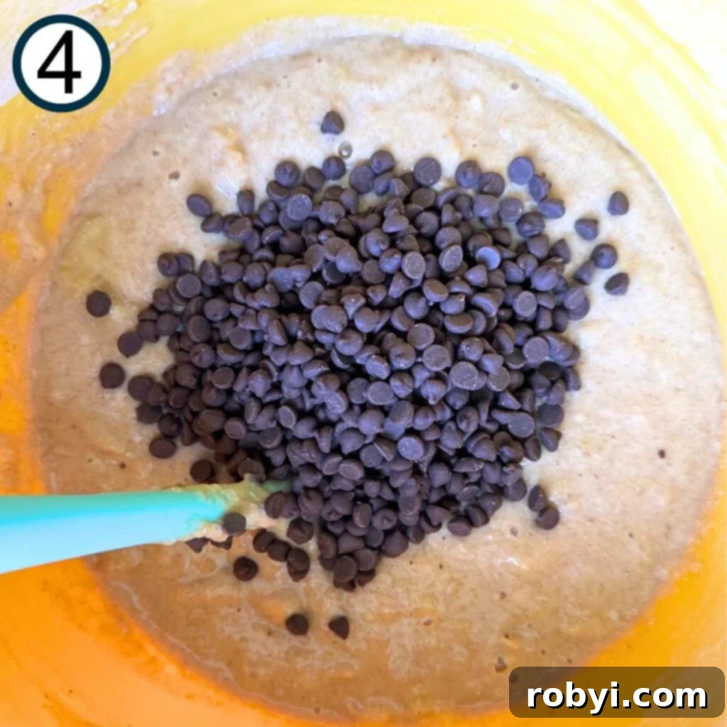 Mini chocolate chips on top of the banana muffin batter, ready to be folded in.