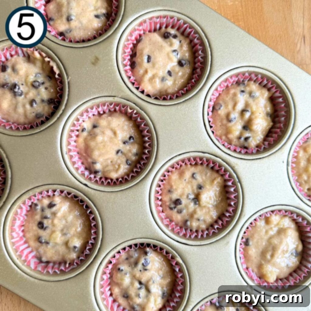 Banana muffin batter in paper inserts in a cupcake pan, showing proper filling level.
