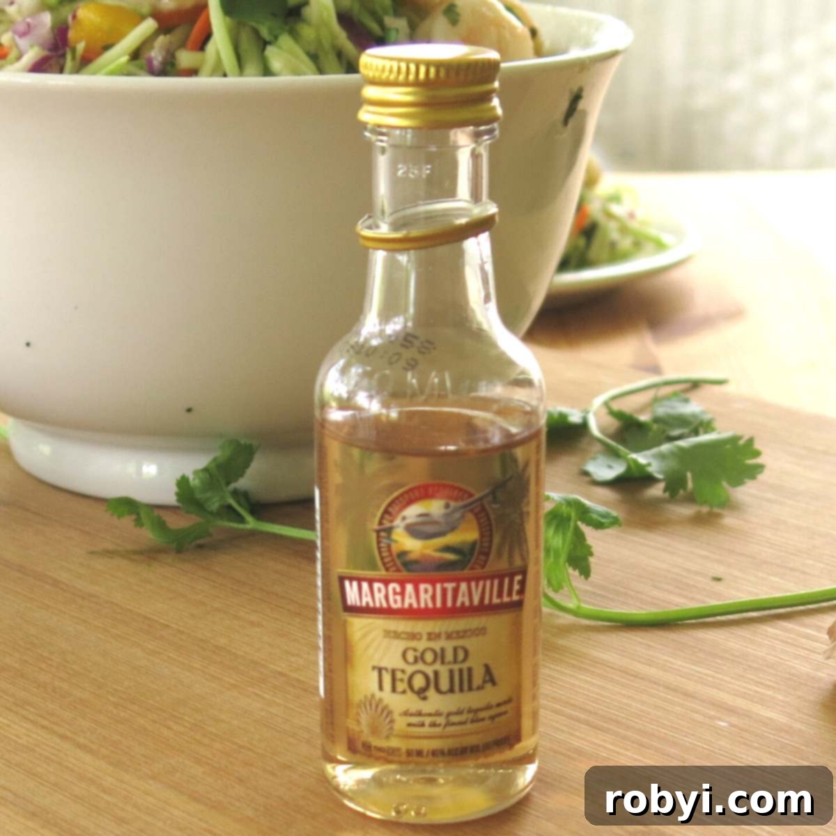 Small bottle of Margaritaville Gold Tequila next to a bowl of raw shrimp.