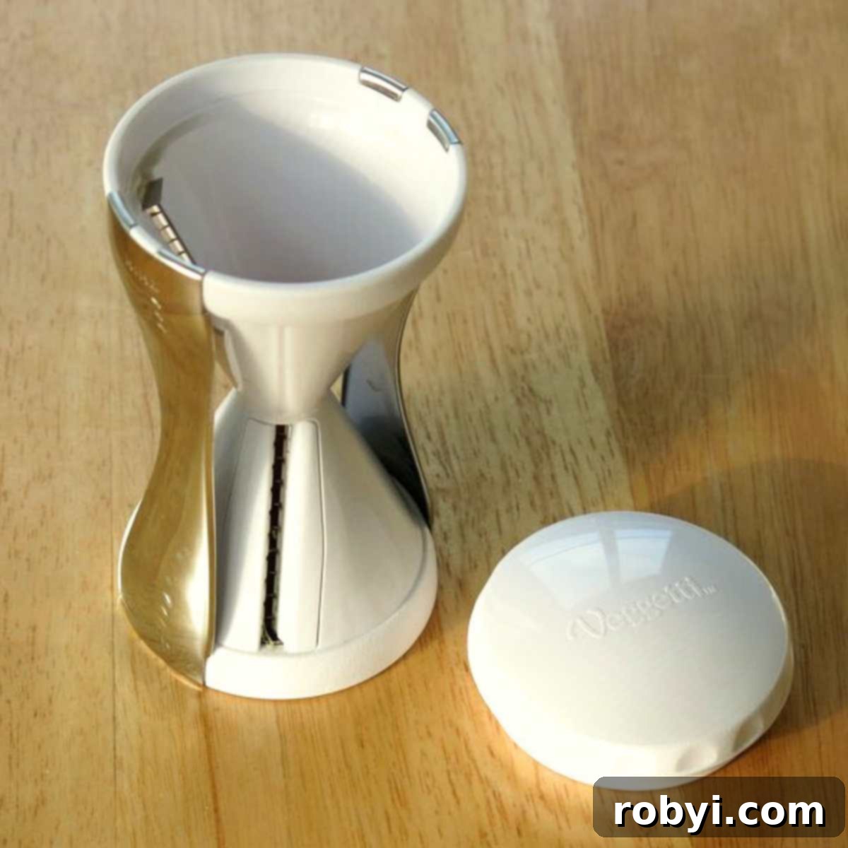 A handheld spiralizer with its top removed, resting on a wooden cutting board, ready for use.