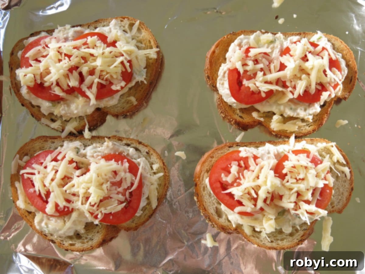Uncooked open-faced tuna melt sandwiches on a baking sheet, ready for broiling