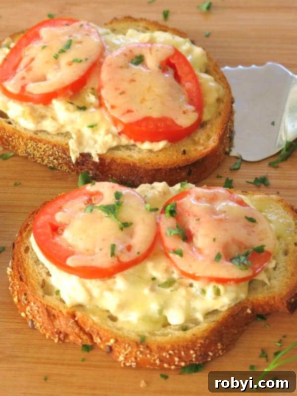 Two Open-Face Tuna Melt Sandwiches with a spatula lifting one from a plate