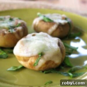 Three mushroom cap pizza bites on a green plate.