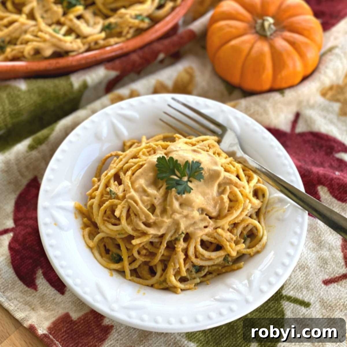 Velvety Pumpkin Pasta Sauce 2 Bowl with creamy pumpkin pasta sauce over spaghetti noodles, garnished with fresh herbs.