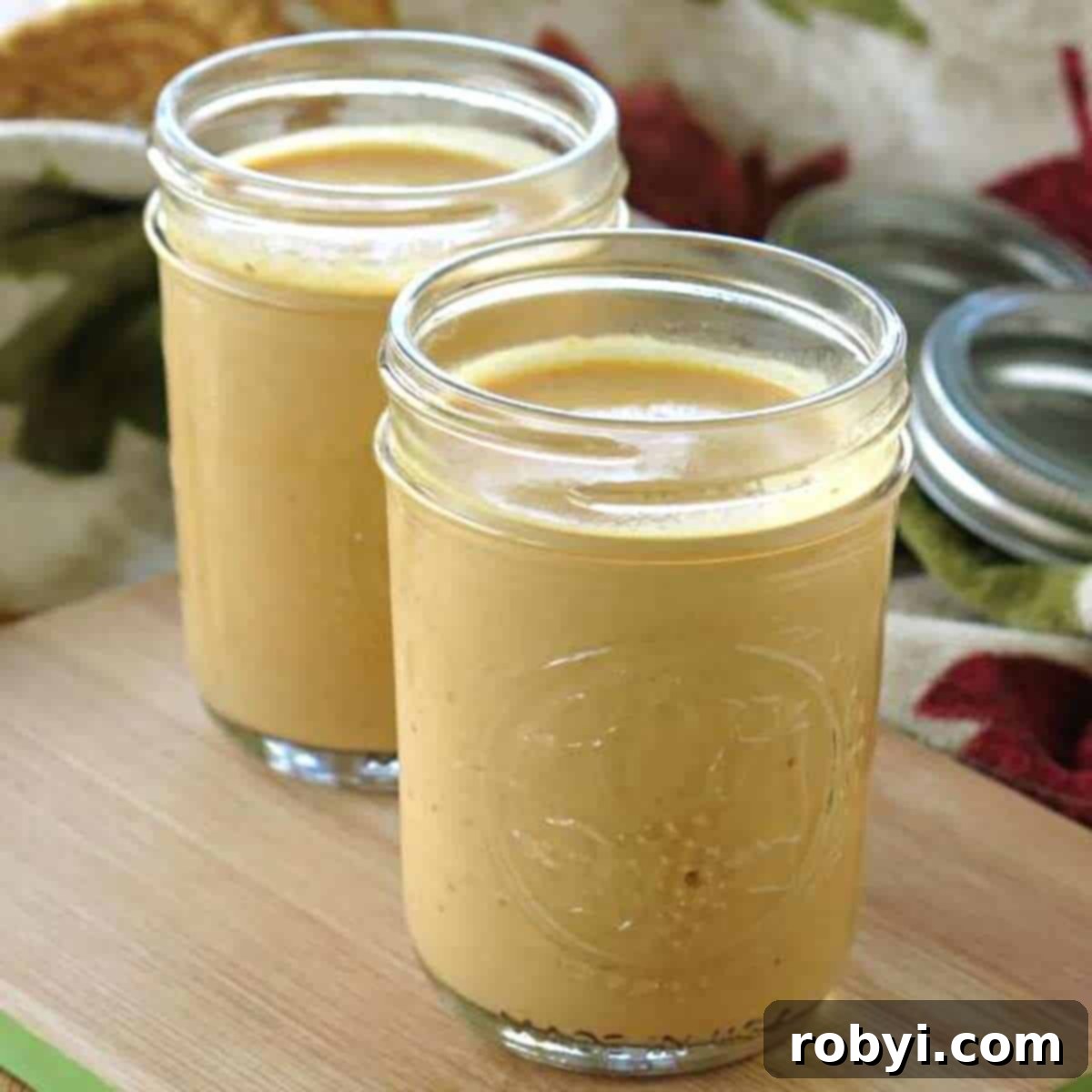 Two clear Mason jars filled with the rich, orange pumpkin pizza sauce, indicating its excellent storage potential for future use.