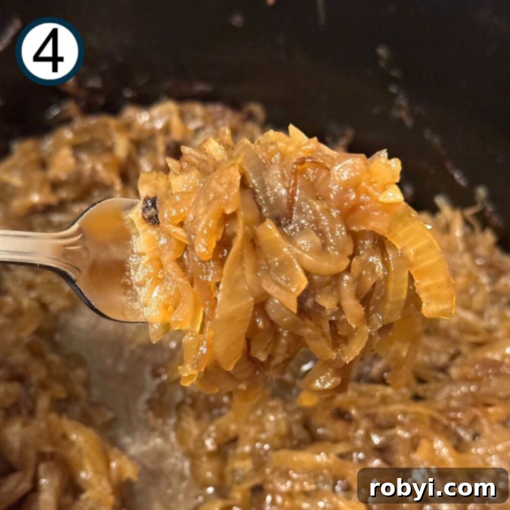 A fork lifting a spoonful of rich caramelized onions out of a slow cooker, showcasing their texture.