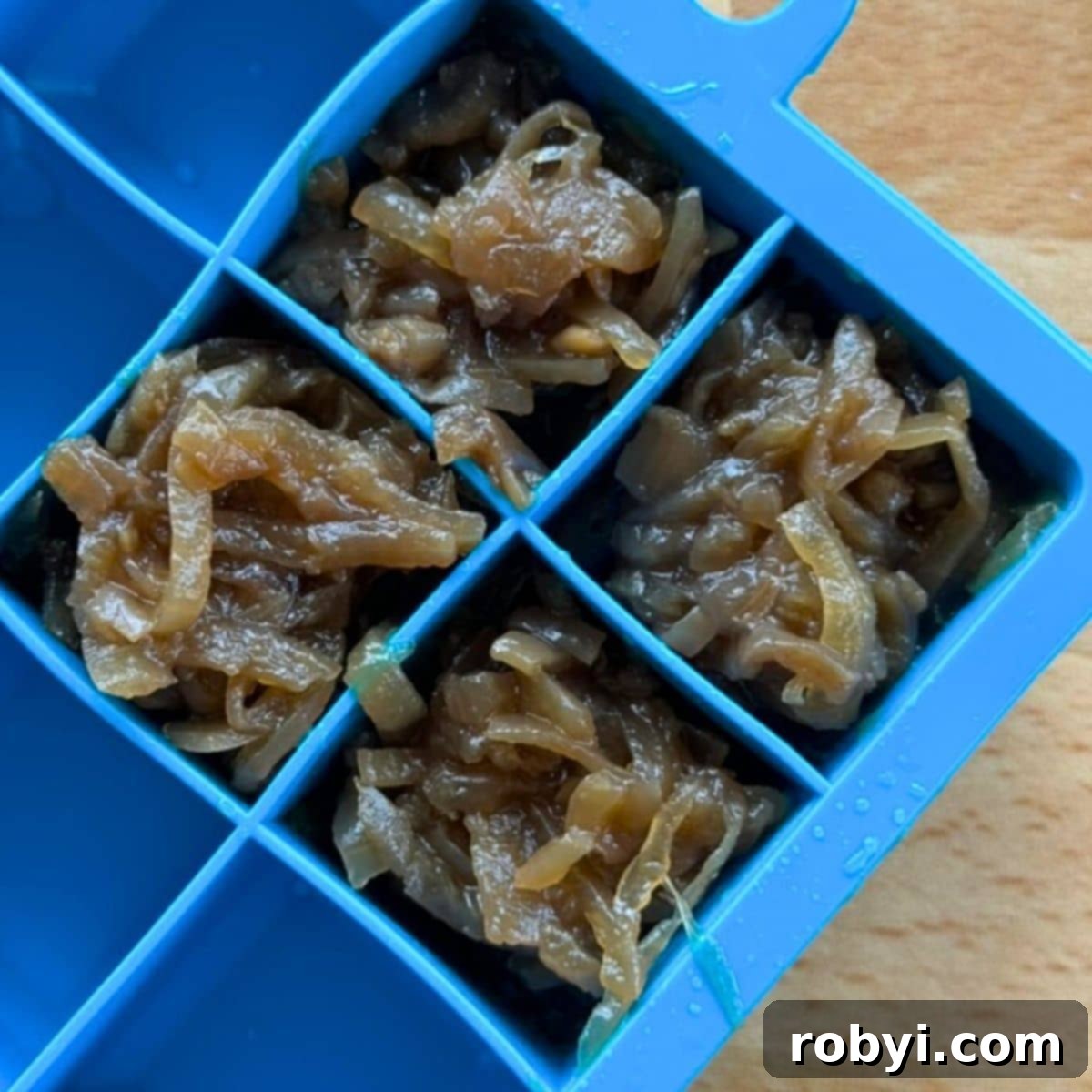 Caramelized onions neatly portioned into an ice cube tray, ready for the freezer.