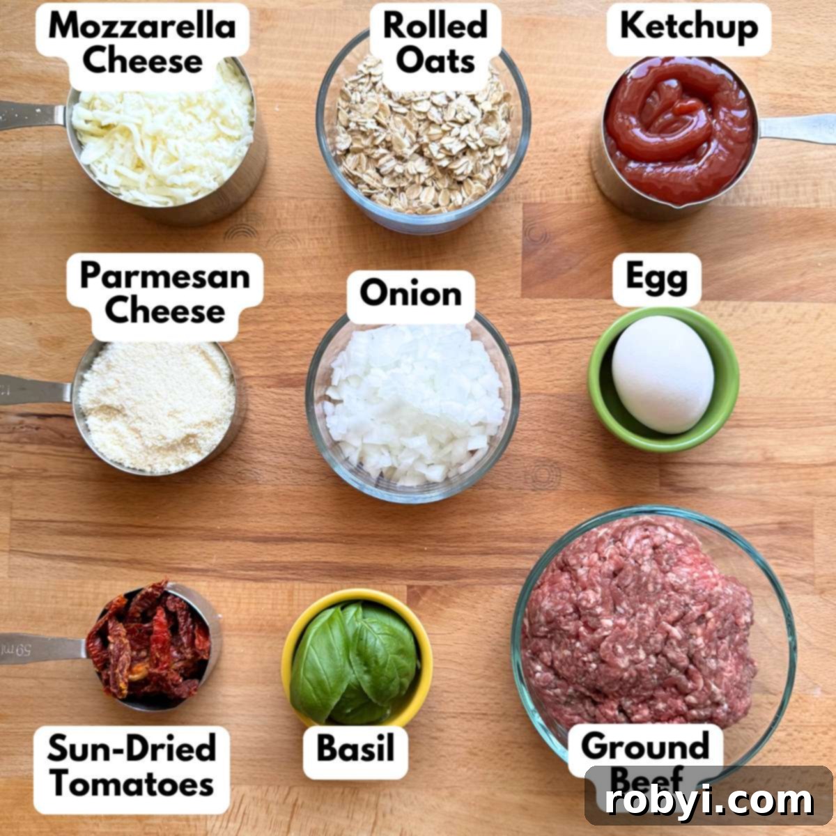 Ingredients to make gourmet meatloaf recipe: mozzarella cheese, rolled oats, ketchup, Parmesan cheese, onion, egg, sun-dried tomatoes, basil leaves, and ground beef arranged on a countertop.