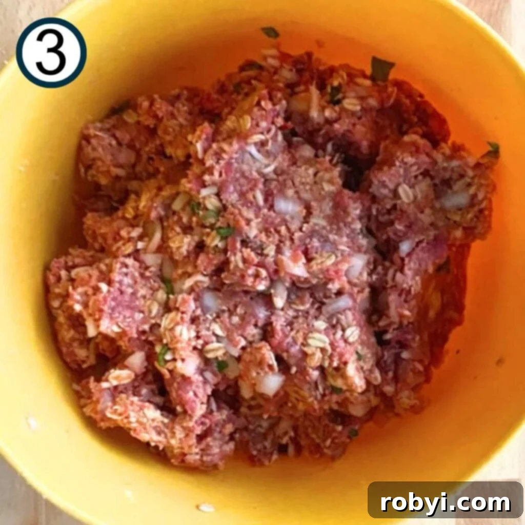 Ground beef added to the other ingredients to form the meatloaf mixture in a large bowl.