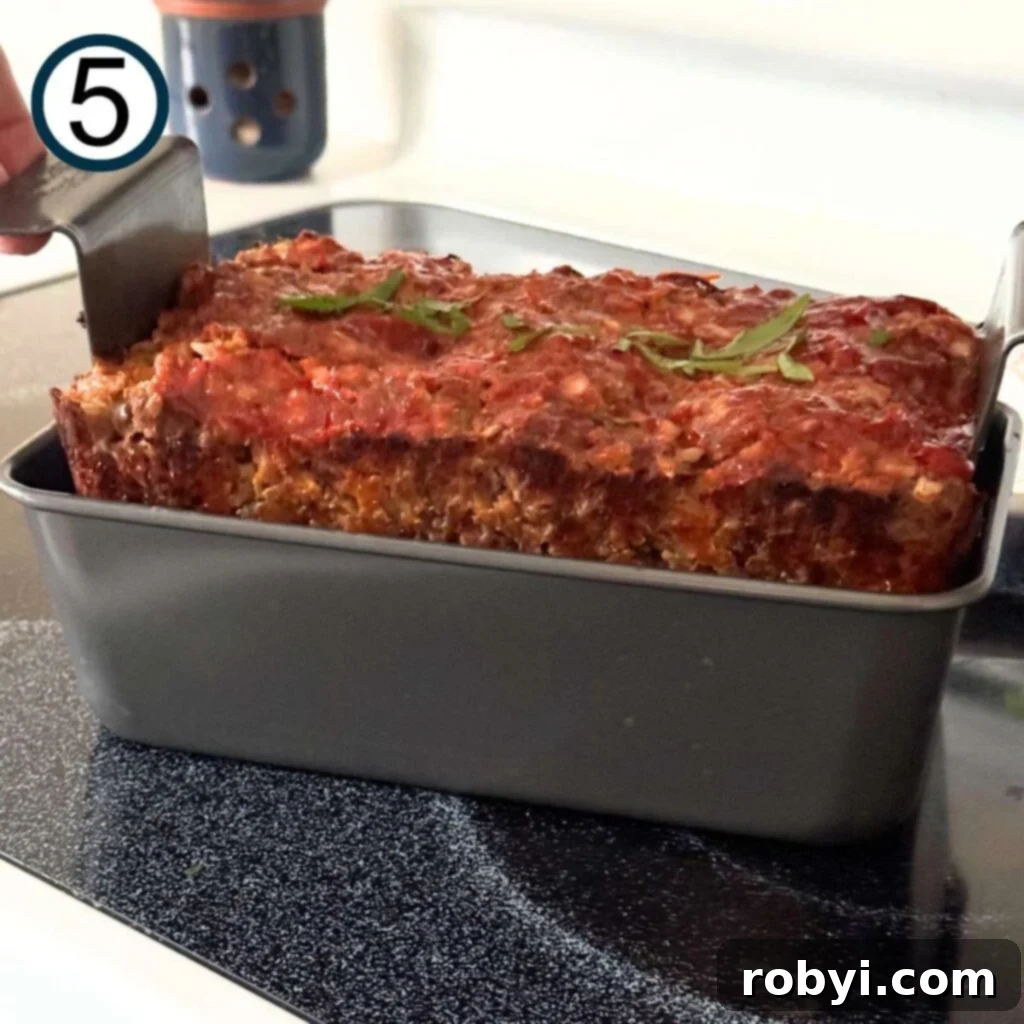 Cooked meatloaf being removed from the pan, showing a perfectly golden-brown crust.