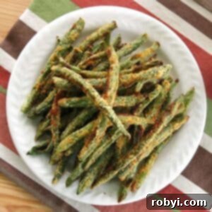 Oven-Crisped Green Bean Fries 5 Keto-friendly, baked green bean fries coated in Parmesan cheese on a plate.