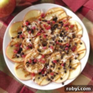 Wholesome Apple Nachos 5 Healthy apple nachos topped with almond butter, granola, chocolate chips, and coconut on a plate.