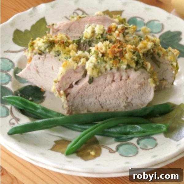 Aromatic Herb-Roasted Pork Tenderloin 2 Sliced Herb Roasted Pork Tenderloin on plate with vibrant green beans and lemon wedge