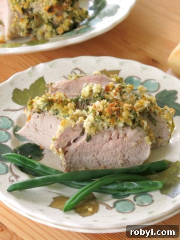 Aromatic Herb-Roasted Pork Tenderloin 5 Artfully plated slices of Herb Crusted Pork Tenderloin on a white plate, showcasing the golden crust and juicy interior