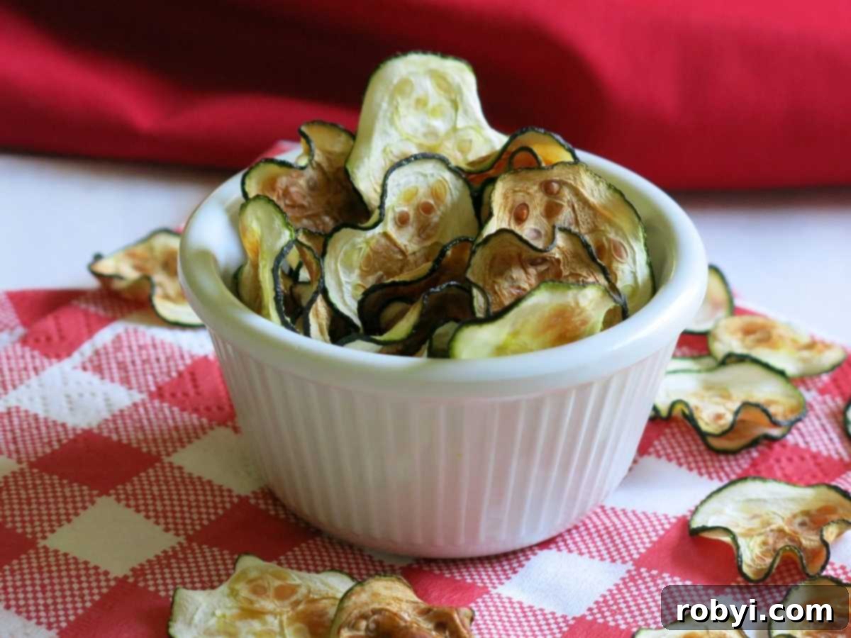 Zucchini chips standing in a serving cup with more on the napkin below.