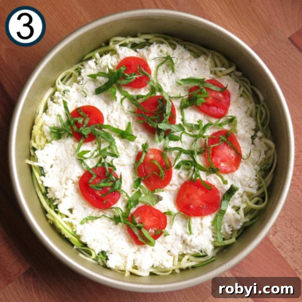 Naked Zucchini Noodle Tart 6 Finely sliced tomatoes and freshly chopped basil leaves artfully arranged over the cheesy layer of the zucchini pie, ready for baking.