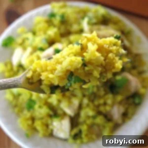 Curry cauliflower rice on a fork with more in a bowl below it.