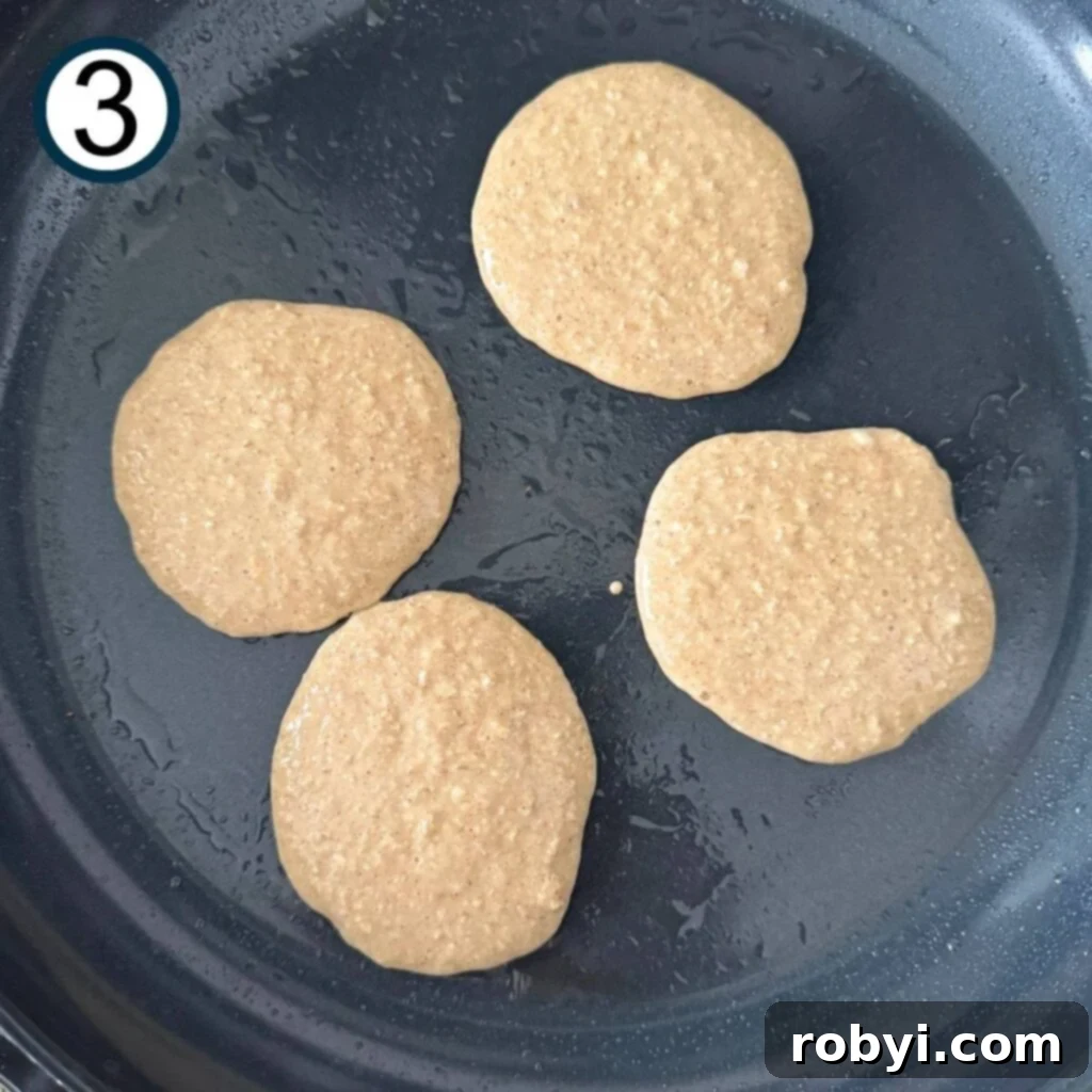 Partially cooked cottage cheese and oat pancakes in a non-stick pan
